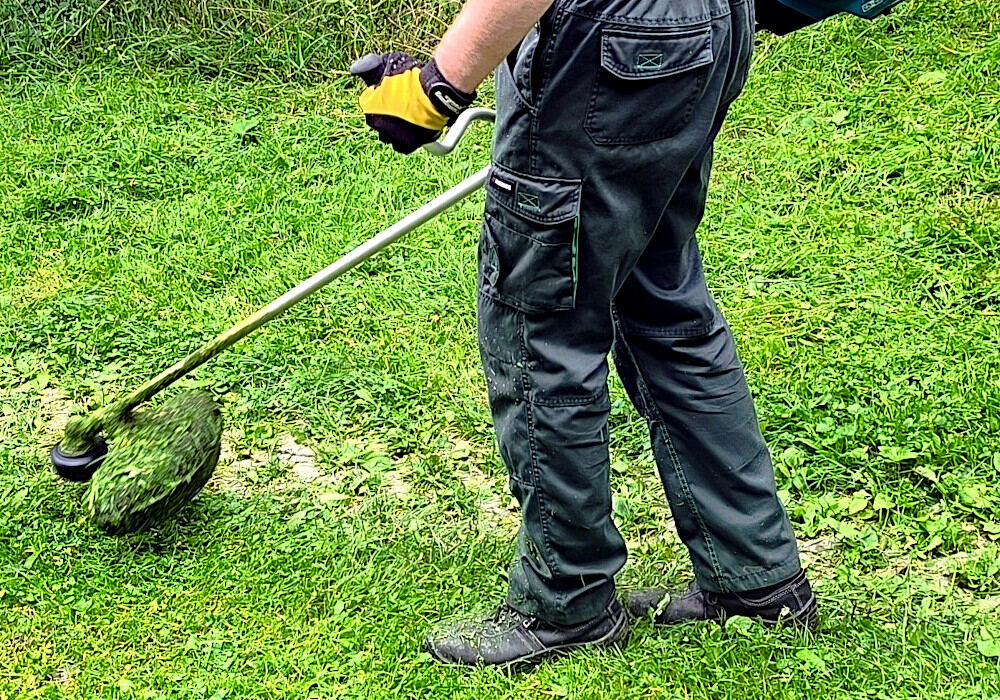 Clearing tall grass and invasive brush using a brush cutter in difficult terrain